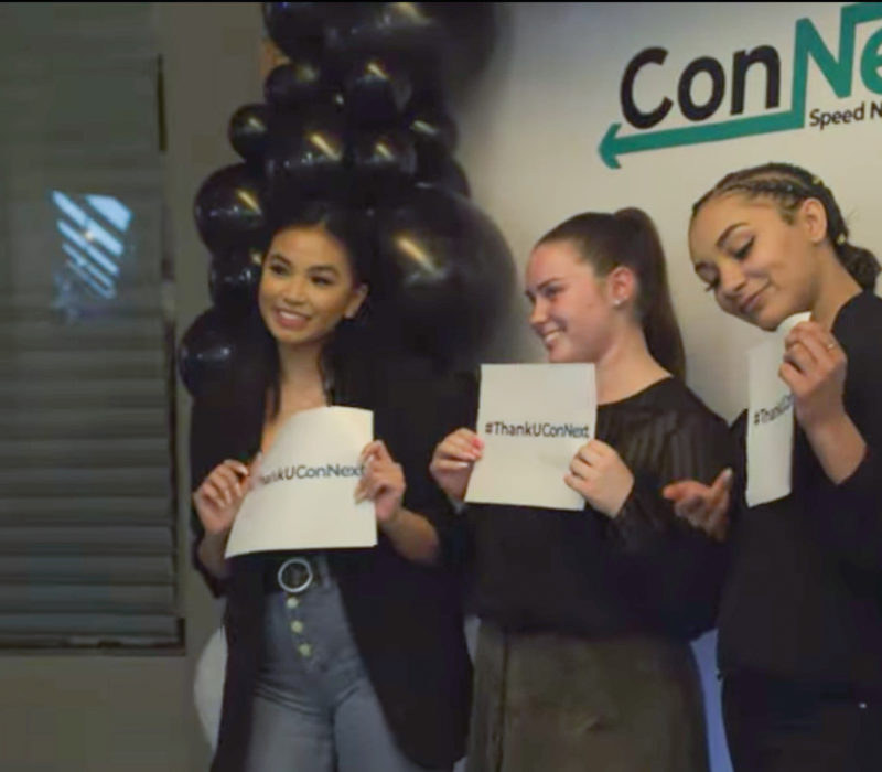 three people holding up connext signs and smiling