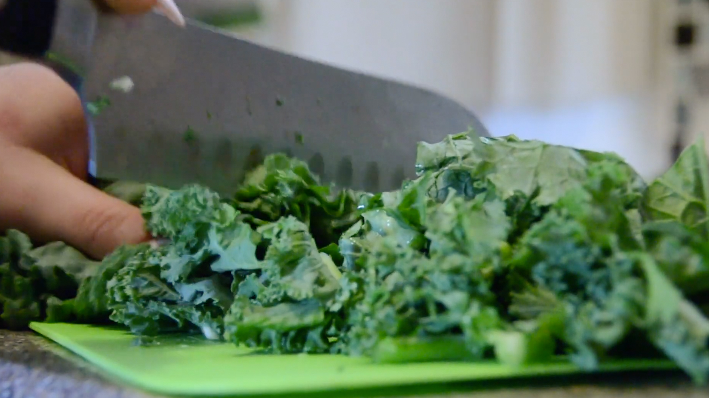 close up of knife chopping kale